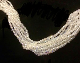 May include: A strand of clear crystal beads with a slight iridescent shimmer. The beads are small and round, and they are strung together on a clear thread.