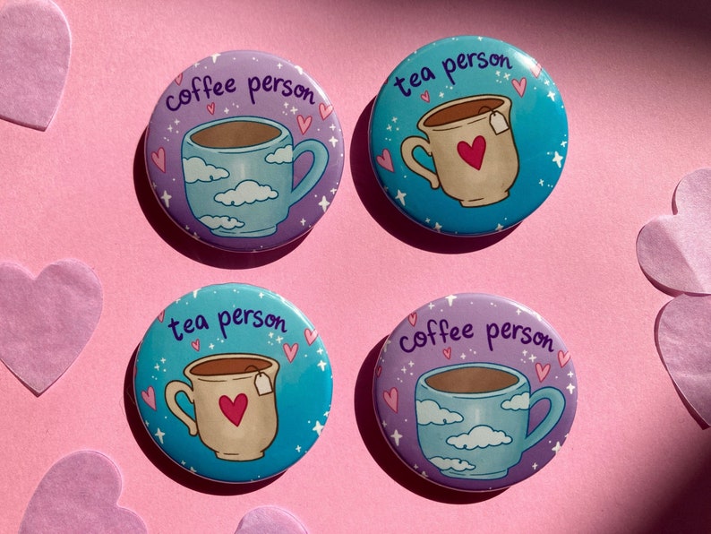 May include: Four circular badges featuring coffee and tea mug illustrations. Two say "coffee person" and two say "tea person". The mugs have heart and cloud designs. The background is pink.
