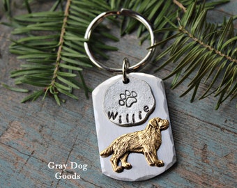 May include: Silver dog tag keychain with a gold paw print and the name "Willie" engraved on it. The tag also features a gold silhouette of a dog.