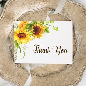 May include: A white card with a sunflower border and the text "Thank You" in brown cursive writing.