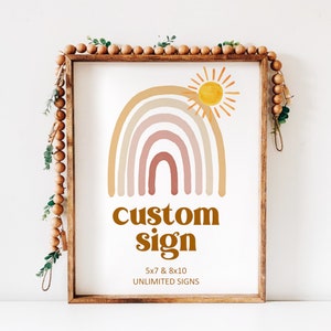 May include: A digital print with a rainbow and sun design. The rainbow is in shades of pink, orange, and yellow. The sun is yellow. The text below the rainbow reads 'custom sign' in brown text. The text below the sign reads '5x7 & 8x10 UNLIMITED SIGNS'.