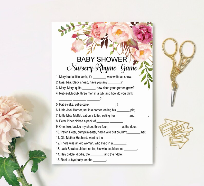 Op de afbeelding: Een roze en groene baby shower-spelkaart met de titel "Nursery Rhyme Game". De kaart bevat 15 rijm-invulvragen.