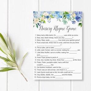 May include: A printable Nursery Rhyme Game card with a floral design in blue and white. The game features fill-in-the-blank nursery rhyme questions. A sprig of greenery is on the left side of the card.
