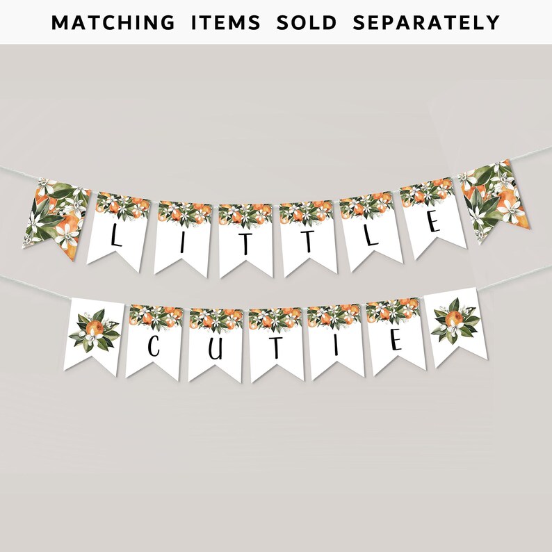 May include: A white banner with orange blossom and fruit designs. The banner spells out "Little Cutie" in black letters.