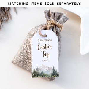 Pode incluir: Uma etiqueta de presente branca com uma ilustra&ccedil;&atilde;o em aquarela de uma cordilheira e uma floresta. A etiqueta est&aacute; amarrada com um barbante a um pequeno saco de juta. O texto na etiqueta diz "FULLY EDITABLE Custom Tag 2"x3.5"