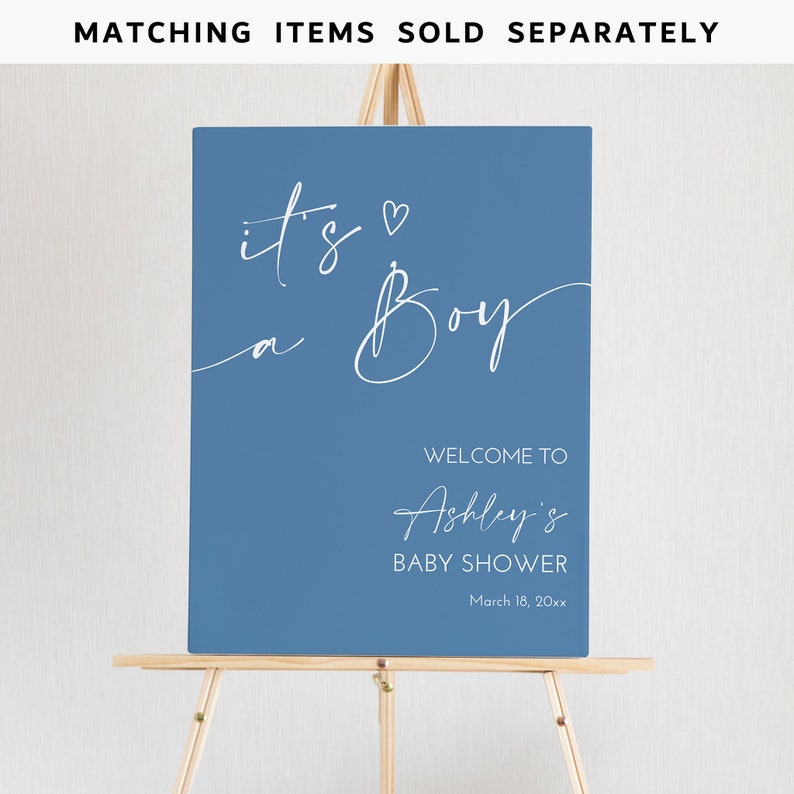 Op de afbeelding: Een blauw bord op een houten ezel met witte tekst met de tekst "It's a Boy" en "Welcome to Ashley's Baby Shower" met de datum 18 maart 20xx. De woorden "Bijpassende items apart verkocht" staan bovenaan.