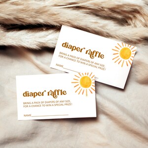 May include: Two white cards with the text "diaper raffle" in brown letters with a yellow sun graphic. The text reads "Bring a pack of diapers of any size, for a chance to win a special prize!" with a line for a name.