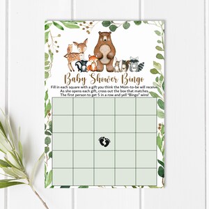 May include: A green and brown baby shower bingo card with a woodland animal theme. The card has a grid of squares with a footprint in the center square. The text on the card reads "Baby Shower Bingo" and includes instructions for playing the game.