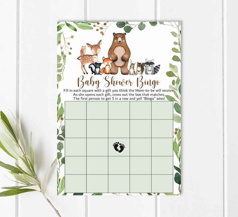 May include: A green and brown baby shower bingo card with a woodland animal theme. The card has a grid of squares with a footprint in the center square. The text on the card reads "Baby Shower Bingo" and includes instructions for playing the game.