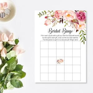 Puede incluir: Una tarjeta de bingo de despedida de soltera imprimible con un dise&ntilde;o floral. La tarjeta tiene un t&iacute;tulo que dice "Bridal Bingo" e instrucciones para rellenar cada casilla con un regalo que la novia recibir&aacute;. La primera persona en obtener 5 en una fila gana.