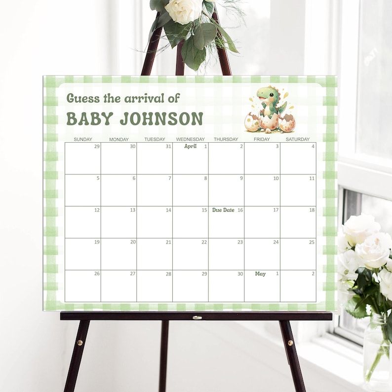 May include: A baby shower calendar on an easel, with a green and white gingham border. The text reads "Guess the arrival of BABY JOHNSON." A cartoon dinosaur and eggs are in the top right corner. The calendar grid is for April and May.
