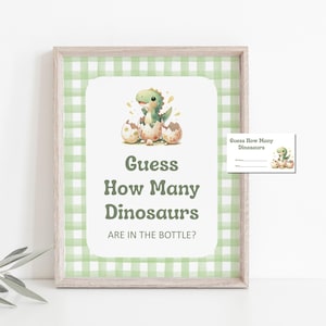 May include: A framed print with a green gingham pattern and a white central panel. It features a watercolour illustration of a baby dinosaur hatching from an egg. The text reads "Guess How Many Dinosaurs Are in the Bottle?" A matching game card is also included.