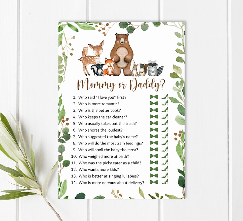 May include: A printable game card with a woodland animal theme. The card has a brown bear, a deer, a fox, a raccoon, and an owl. The text on the card reads "Mommy or Daddy?" and includes a list of 14 questions about the parents-to-be.