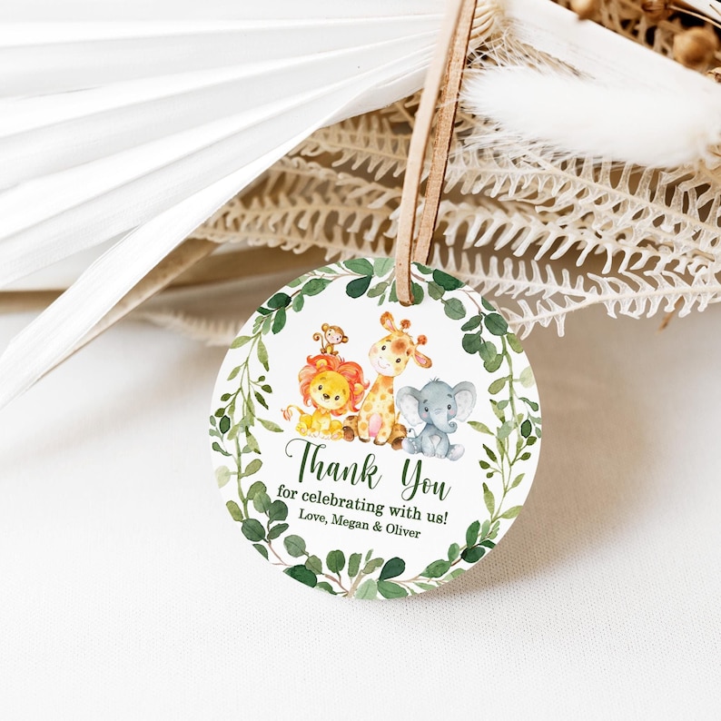 May include: Round thank you tag with a green leafy border. The tag features a lion, giraffe, monkey, and elephant with the text "Thank You for celebrating with us! Love, Megan & Oliver"
