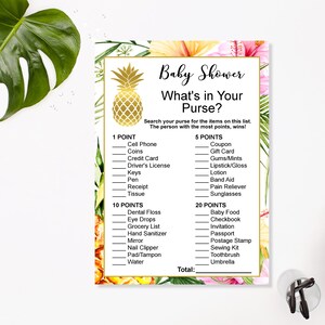May include: A printable baby shower game card with a tropical theme. The card has a pineapple graphic and text that reads "Baby Shower What's in Your Purse?" The game asks players to search their purses for items on a list and award points for each item found.