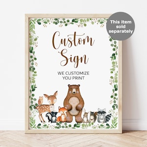 May include: A printable sign with a woodland theme. The sign says "Custom Sign" and "We Customize You Print". The sign features a brown bear, a deer, a fox, a raccoon, a squirrel, and an owl. The sign is surrounded by a green leafy border.