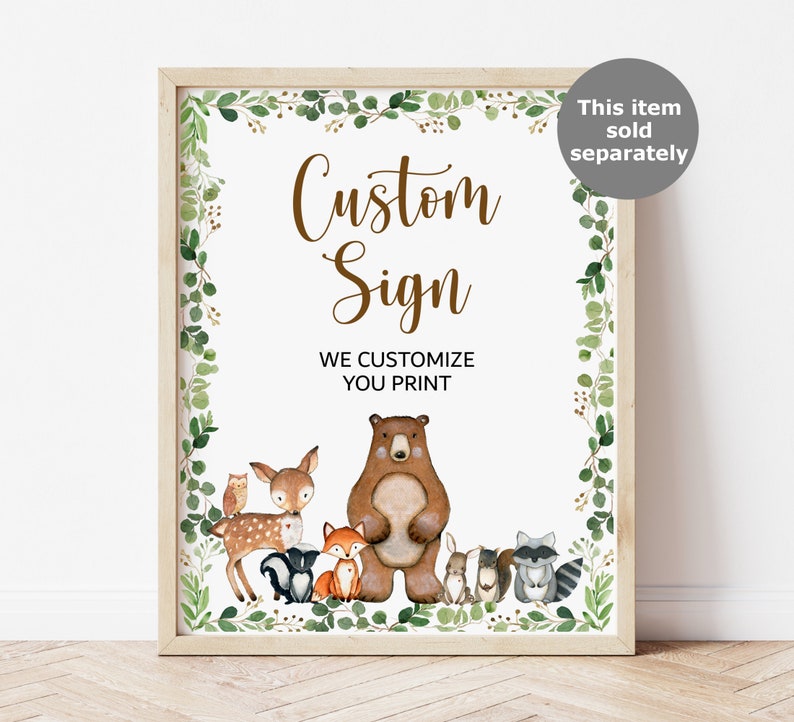 May include: A printable sign with a woodland theme. The sign says "Custom Sign" and "We Customize You Print". The sign features a brown bear, a deer, a fox, a raccoon, a squirrel, and an owl. The sign is surrounded by a green leafy border.