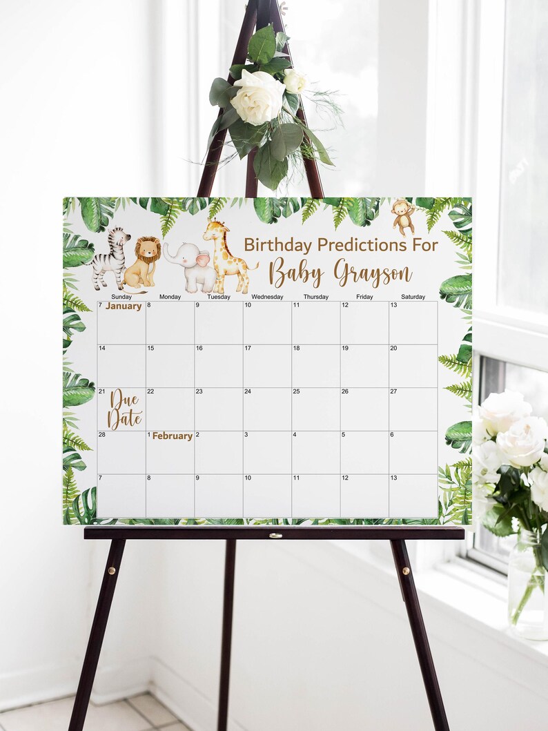 May include: A white calendar with a jungle theme, featuring illustrations of a zebra, lion, elephant, giraffe, and monkey. The calendar is for "Baby Grayson" with the text "Birthday Predictions For." It is displayed on a wooden easel.