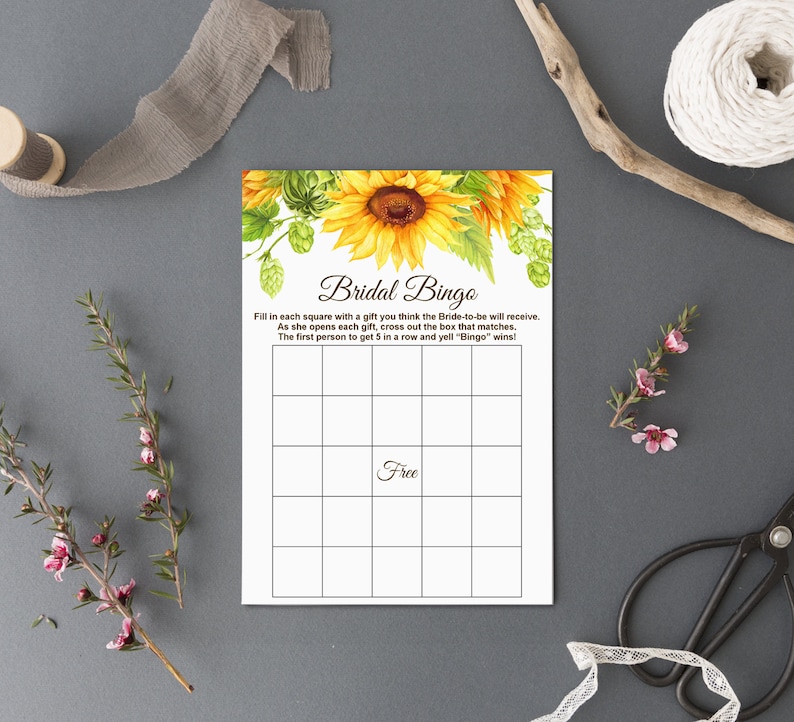 May include: A printable bridal bingo card with a sunflower illustration. The card has a 5x5 grid with squares to fill in with gifts the bride-to-be will receive. The text on the card reads "Bridal Bingo" and includes instructions for playing the game.