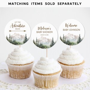 Pode incluir: Tr&ecirc;s toppers para cupcake com tema de floresta. Os toppers apresentam uma cena de montanha em aquarela com &aacute;rvores e um lago. O texto nos toppers diz "Let the Adventure Begin", "Melissa's Baby Shower August 24, 20XX", e "Welcome Baby Johnson".