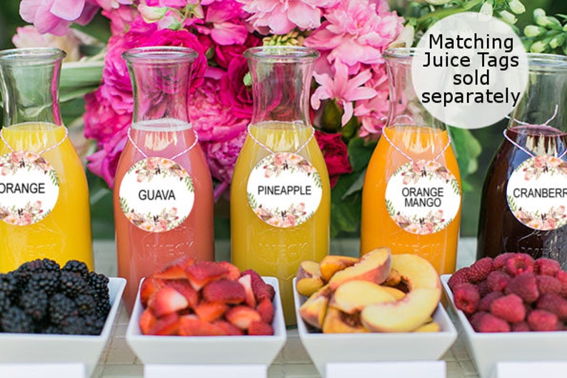 Pode incluir: Uma mesa com cinco garrafas de vidro cheias de sucos de diferentes cores. Cada garrafa tem uma etiqueta redonda com um design floral e o nome do suco: Laranja, Goiaba, Abacaxi, Manga Laranja e Cranberry. H&aacute; tigelas de frutas na frente de cada garrafa: amoras, morangos, fatias de p&ecirc;ssego e framboesas.