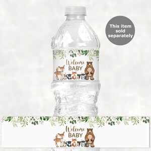 May include: Water bottle label with a woodland theme. The label features a brown bear, a deer, a fox, a raccoon, and a squirrel. The text on the label reads "Welcome Baby".