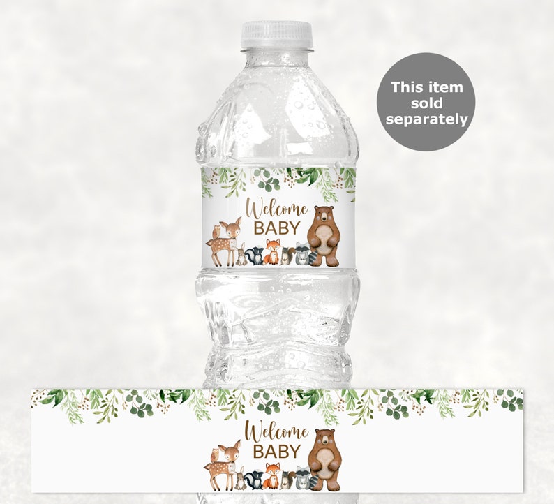 May include: Water bottle label with a woodland theme. The label features a brown bear, a deer, a fox, a raccoon, and a squirrel. The text on the label reads "Welcome Baby".