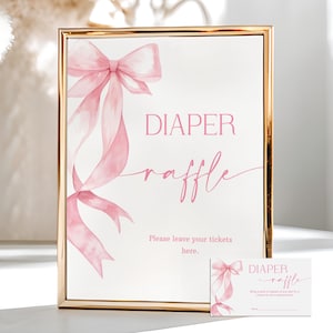 Puede incluir: Un letrero enmarcado con borde dorado, con un lazo y cintas rosas en acuarela. El letrero dice "DIAPER raffle" en escritura rosa, con texto adicional debajo. También hay una tarjeta a juego.