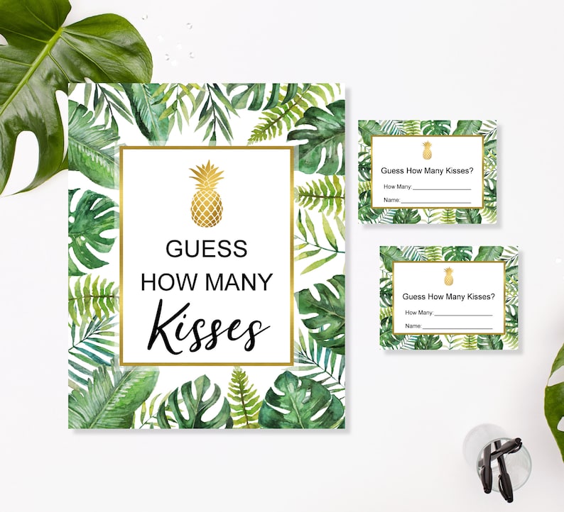 May include: A set of tropical-themed party game cards. The main card features a gold pineapple illustration and the text "Guess How Many Kisses". Smaller cards repeat the game prompt. Green and white foliage frames the cards.