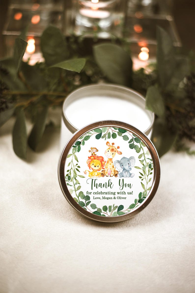 May include: A white candle in a tin container with a green, leafy, and animal-themed label. The label says "Thank You for celebrating with us! Love, Megan & Oliver".