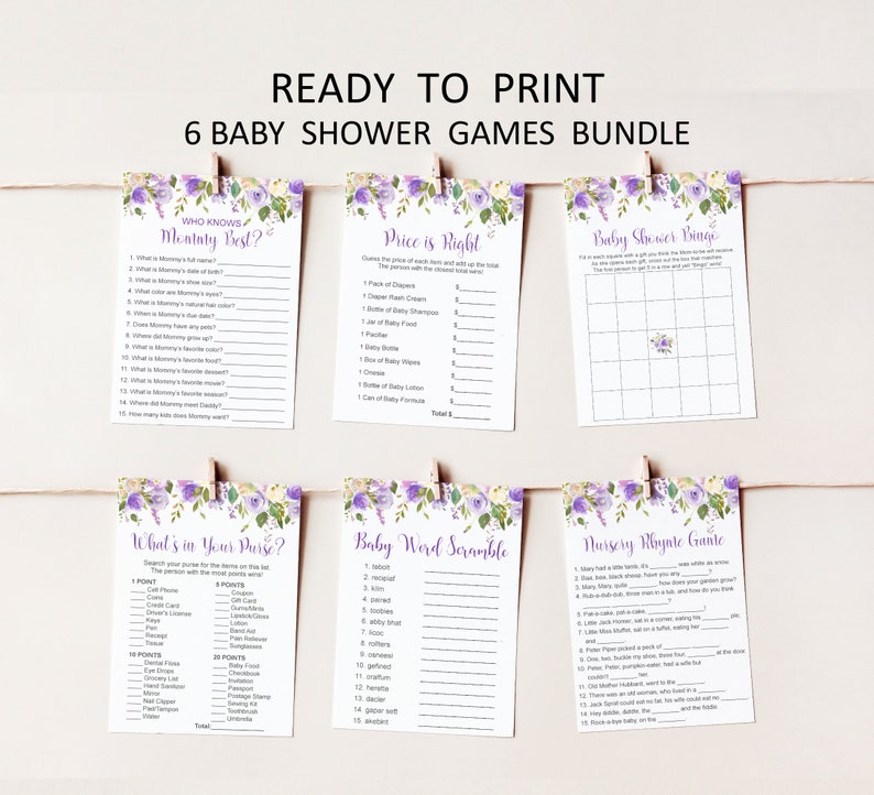 Puede incluir: Seis juegos de baby shower impresos en tarjetas blancas, sujetas con pinzas de madera en una cuerda. Las tarjetas presentan dise&ntilde;os florales morados y t&iacute;tulos de juegos como "&iquest;Qui&eacute;n conoce mejor a mam&aacute;?" y "El precio es correcto".