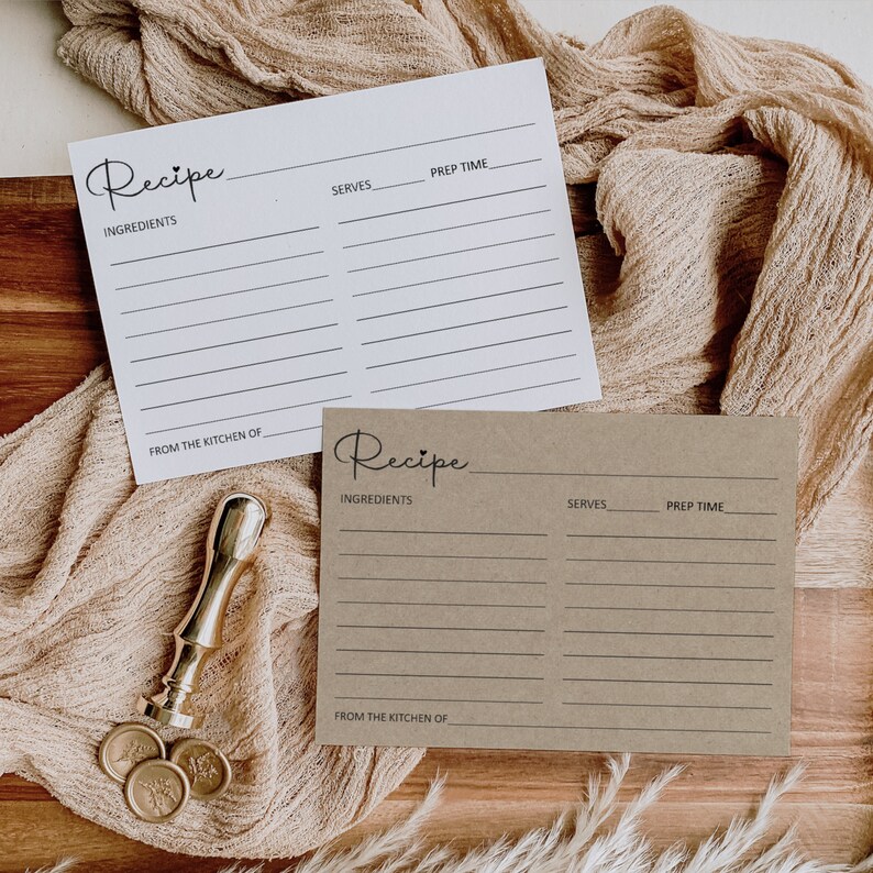 May include: Two recipe cards, one white and one brown, with the word "Recipe" written in cursive at the top. Both cards have lines for ingredients, serves, and prep time. The white card has a line for "From the kitchen of" at the bottom. The brown card has a heart symbol next to the word "Recipe".