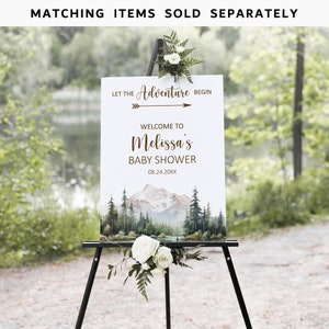 Pode incluir: Uma placa branca com uma cena de montanha em aquarela e o texto "Let the Adventure Begin" com uma seta apontando para a direita. O texto "Welcome to Melissa's Baby Shower" e a data "08.24.20XX" est&atilde;o abaixo da seta. A placa est&aacute; em um cavalete preto.
