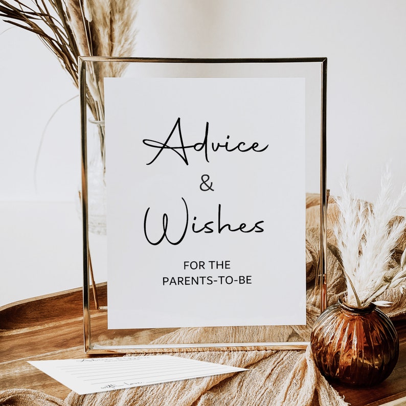 May include: A gold-framed sign with white paper inside. The sign says "Advice & Wishes for the Parents-to-Be".