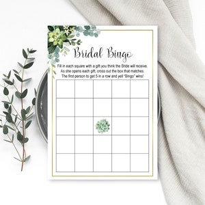 May include: A printable bridal bingo card with a green succulent illustration in the center. The text reads "Bridal Bingo" and includes instructions for playing the game.