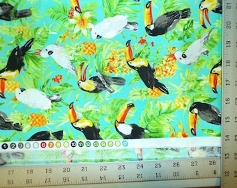 May include: Turquoise fabric with a tropical print featuring toucans, cockatoos, pineapples, and green leaves. The fabric is measured with a ruler.