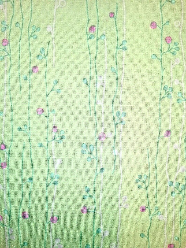 May include: A green fabric with a repeating pattern of white and green stems with pink flowers.