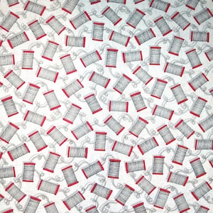 May include: White fabric with a repeating pattern of red and black spools of thread. The spools are drawn in a simple line art style.