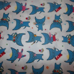 May include: White fabric with a repeating pattern of blue cats wearing different hats and accessories. The cats are all facing forward and have a whimsical expression.