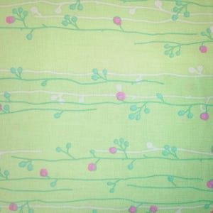 May include: A green fabric with a white and light green floral pattern. The pattern features small pink flowers and leaves.
