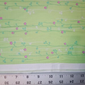 May include: Green fabric with a white and light green floral pattern. The fabric has a subtle sheen and a soft texture.
