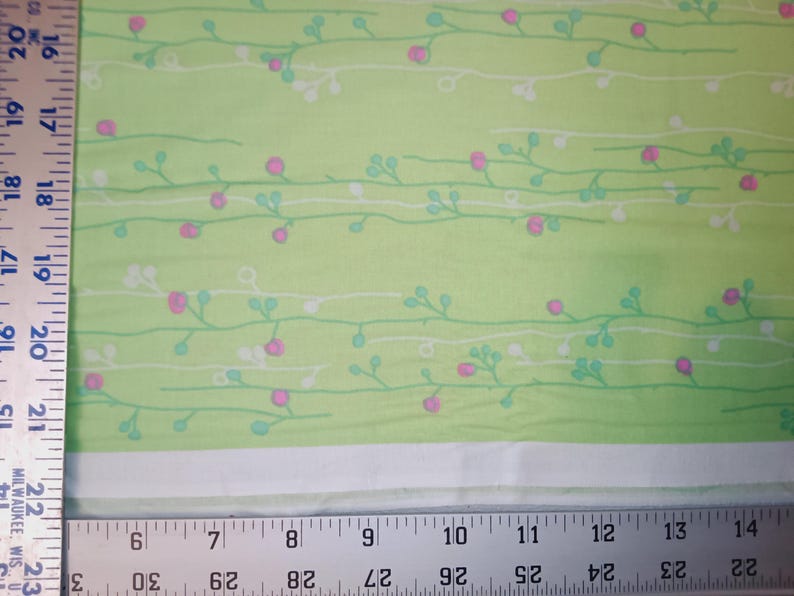 May include: Green fabric with a white and light green floral pattern. The fabric has a subtle sheen and a soft texture.