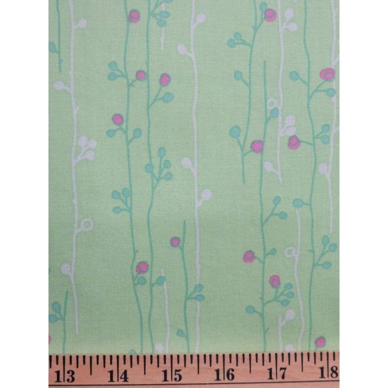May include: Green fabric with a white and light blue floral pattern. The fabric has a repeating pattern of small flowers and stems.