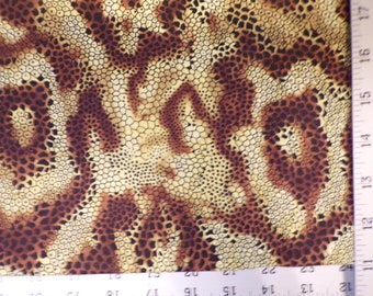 May include: Close-up of a fabric with a brown and tan animal print pattern. The pattern features irregular shapes and small, dark brown spots against a lighter tan background. The fabric has a textured appearance.