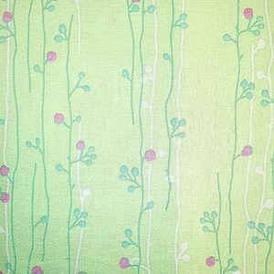 May include: A green fabric with a white and green floral pattern. The flowers are small and pink.