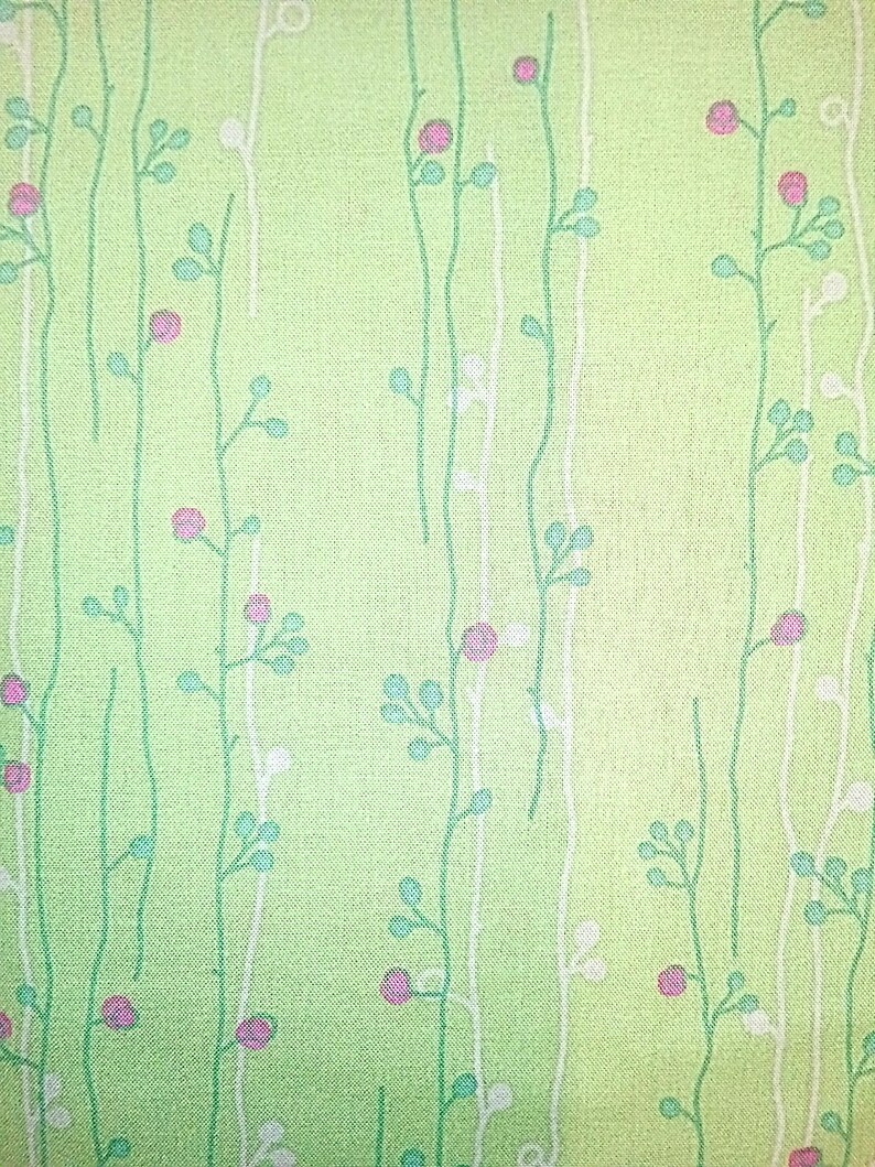 May include: A green fabric with a white and green floral pattern. The flowers are small and pink.