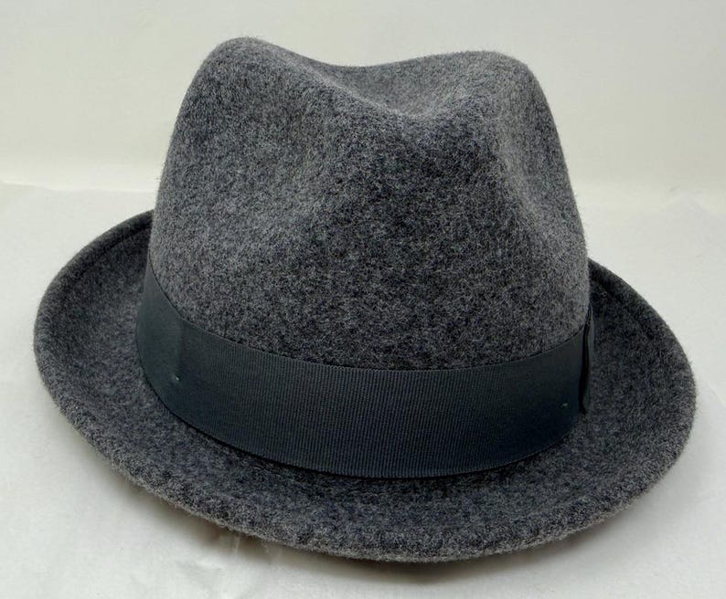 Pode incluir: Um chap&eacute;u fedora cinza-carv&atilde;o com um acabamento texturizado semelhante a feltro. O chap&eacute;u apresenta uma copa estruturada com um vinco central e frente pin&ccedil;ada, complementado por uma larga faixa de fita gorgor&atilde;o preta s&oacute;lida na base.