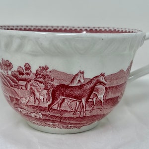 Könnte beinhalten: Eine weiße Teetasse mit einem roten und weißen Blumendesign. Das Design zeigt Pferde und andere Nutztiere in einer ländlichen Umgebung.