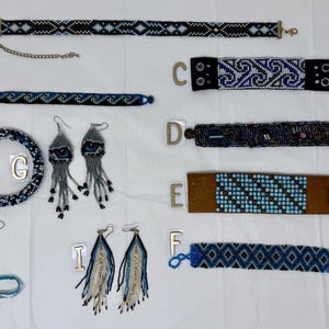 Puede incluir: Una colección de joyas de cuentas, que incluye gargantillas, pulseras y pendientes. Las piezas presentan cuentas azules, negras y blancas en varios patrones. Algunos pendientes tienen largas borlas colgantes. Las joyas se exhiben sobre una superficie blanca.