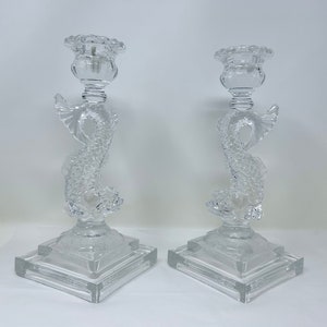 May include: A pair of clear glass candle holders shaped like a fish with a square base.